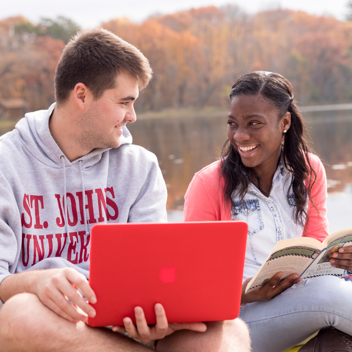 Two students reading and studying at the beach. 