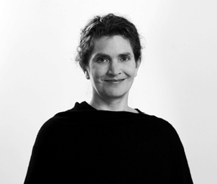 Black and white photo of a woman with short curly hair, wearing a dark top and smiling slightly against a plain background.