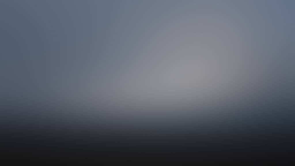 A blurred gradient background transitioning from dark at the bottom to lighter gray and blue tones at the top, creating a soft, hazy, and abstract effect.