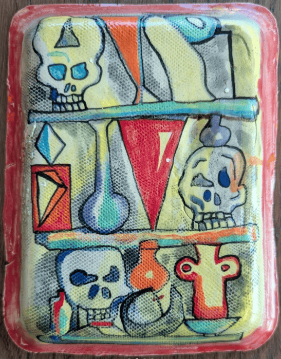 Colorful artwork on a tray, featuring cartoon skulls, geometric shapes, and laboratory glassware on shelves. The background is gray with bright yellow, orange, red, and blue accents. The tray is framed in red.