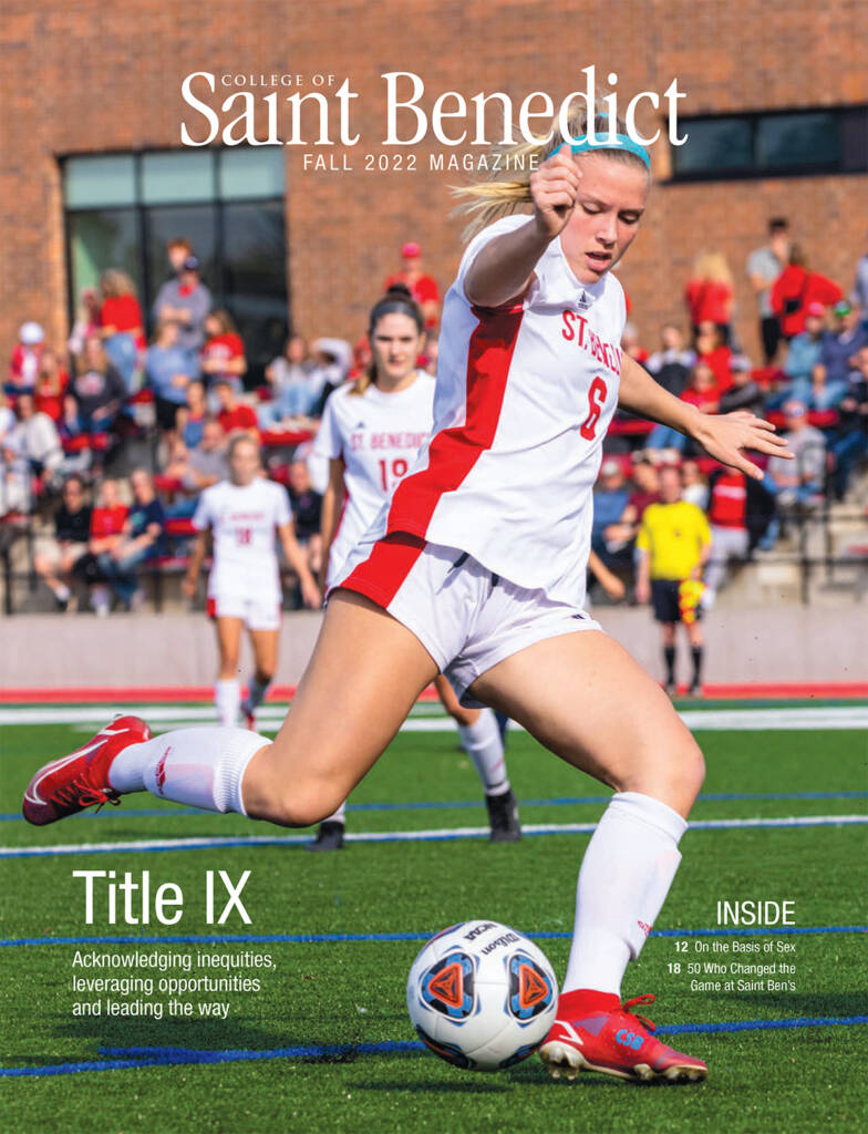 A female soccer player in a white and red uniform is in motion, preparing to kick a soccer ball. The background shows a soccer field with spectators in the stands. Text on image: "College of Saint Benedict Fall 2022 Magazine.