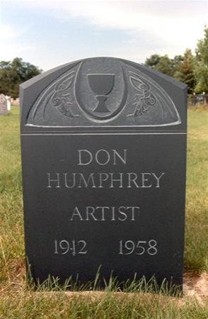 A black gravestone with a chalice and decorative carvings at the top, inscribed with “DON HUMPHREY ARTIST 1912 1958,” standing on grass in a cemetery.
