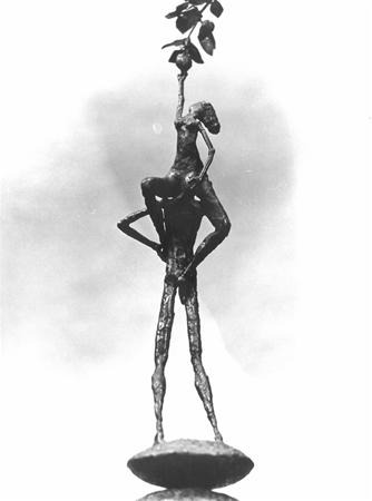 A slender metal sculpture of a tall figure standing with one arm on its hip while a smaller figure sits on its shoulders, reaching upward to touch a leafy branch. The sculpture stands on an oval base.