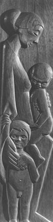 A carved wooden relief shows a woman holding a small child in her arms and resting her other hand on the shoulder of a second child standing beside her. All figures have stylized, serene expressions.