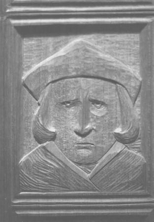 A carved wooden relief of a person with a somber expression, wearing a flat, wide cap and robe, depicted within a rectangular framed border.