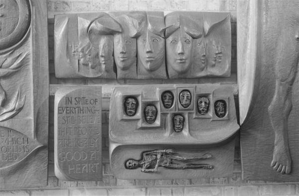 A relief sculpture shows abstract human faces, small faces in rounded frames, a thin figure lying down, and a plaque reading, "In spite of everything I still believe that people are really good at heart.