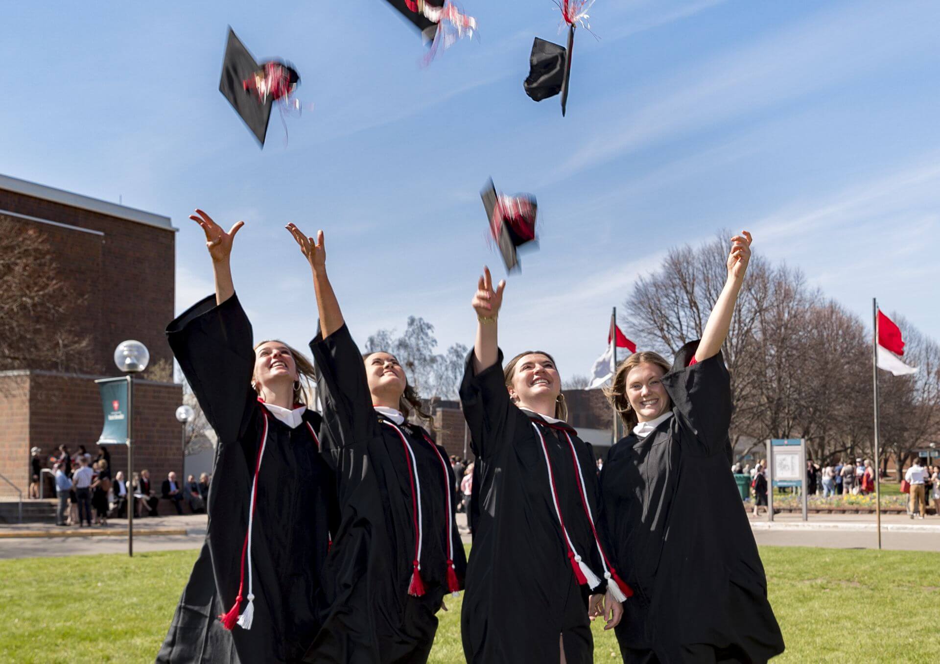 A group of women in graduation gowns throwing caps in the air.