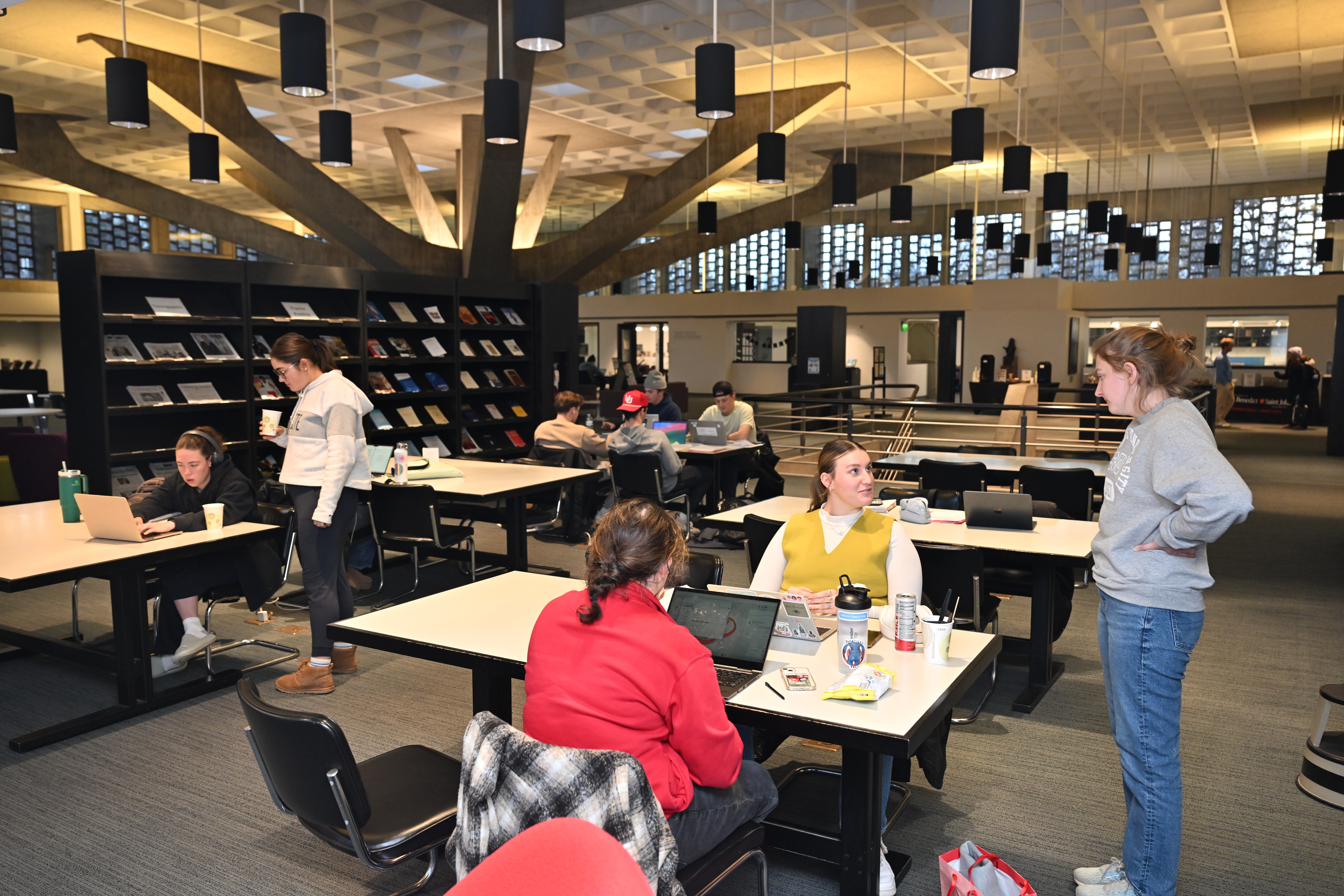 A group of people sitting at tables in a library.