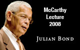 An elderly man with short white hair, wearing glasses and a brown suit, speaks with his mouth slightly open. The text on the right side reads: "McCarthy Lecture 2008 Julian Bond." The background is dark.