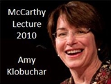 A woman with short, dark hair and glasses is smiling. The text beside her reads "McCarthy Lecture 2010 Amy Klobuchar.