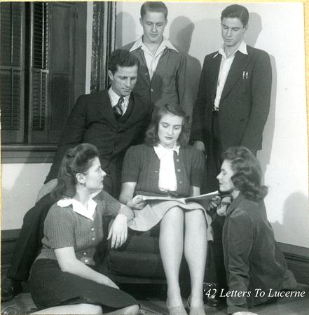 A group of young adults gather in a room. Four are seated, while two stand behind them. One person holds a book open, and the others appear engaged with its contents. A window with shutters is in the background. Text reads "42 Letters to Lucerne.