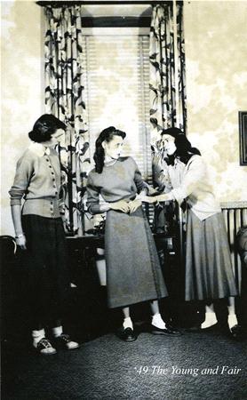 Three women from the 1940s standing in a room with floral curtains, dressed in mid-length skirts and cardigans. They appear to be engaged in conversation, with one gesturing animatedly. Text reads "49 The Young and Fair.