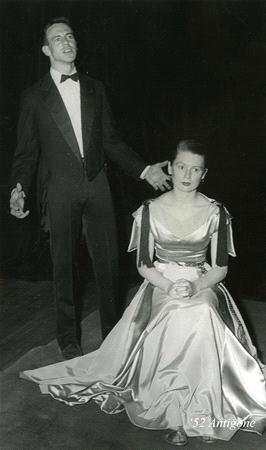 A man in a tuxedo stands singing passionately next to a seated woman in a formal gown. They appear to be performing on stage. The woman's expression is calm as she looks forward. The photo is in black and white, with '52 Arrigoni' written on it.
