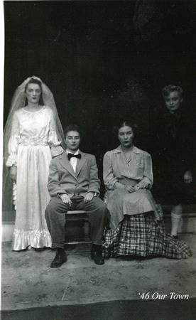 A vintage black and white photo shows four people dressed in theatrical costumes. One person is in a wedding gown, another in a suit, and two others in period dresses. The setting suggests a performance, possibly from a play like "Our Town".