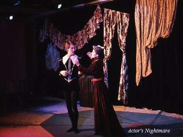 Two actors perform on stage in medieval-style costumes. The background features draped fabric and curtains. The stage lights cast dramatic shadows. In the bottom right, text reads "Actor's Nightmare.