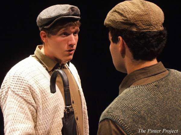 Two men in period clothing face each other. One wears a flat cap and a textured cardigan, holding an umbrella. The other wears a hat and a vest. They appear engaged in conversation on a dimly lit stage. Text at the bottom reads "The Pinter Project.