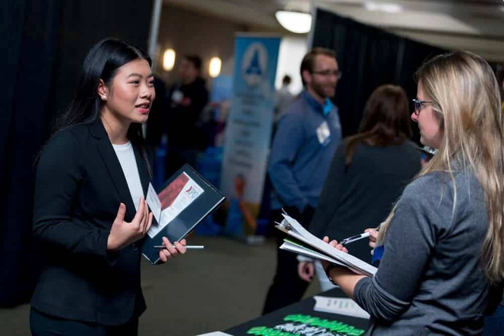 women-speaking-at-a-career-fair-to-a-potential-employer.