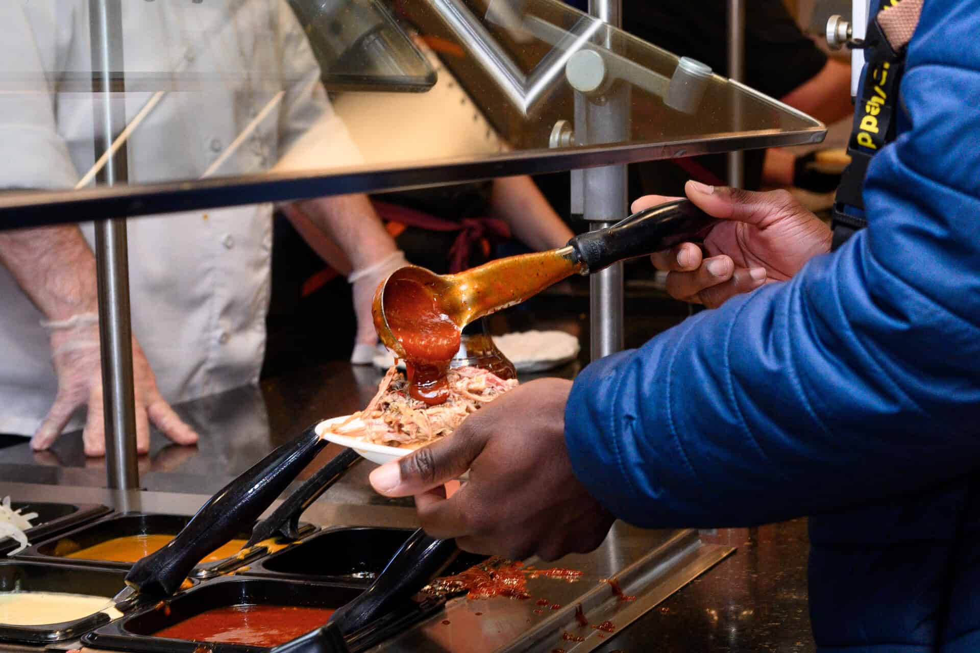 S J U student serves himself tasty dining hall food. 