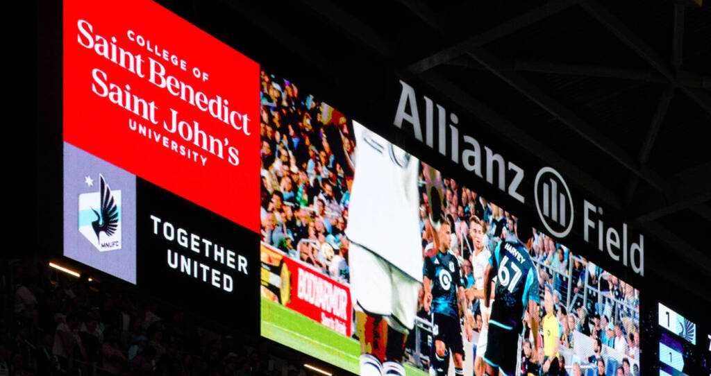 Fans fill the stands at Minnesota United's Allianz Field, highlighted by vibrant LED displays promoting the College of Saint Benedict and Saint John's University.