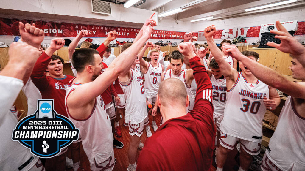 A basketball coach huddles with a team of players wearing white "Johnnies" jerseys in a locker room. They raise their fists in excitement. A "2025 DIII NCAA Men's Basketball Championship" logo is in the corner.